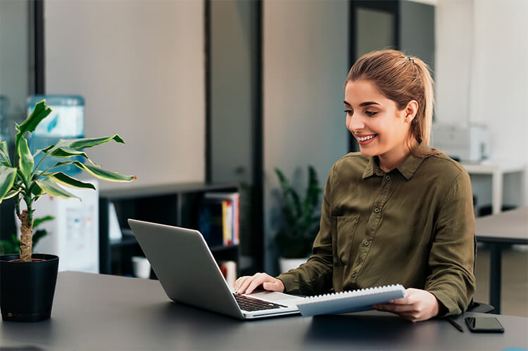 A woman smiling while working on her laptop